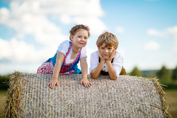 Wall Mural - Two kids, boy and girl in traditional Bavarian costumes in wheat field