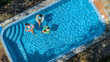 © Iuliia Sokolovska - Aerial top view of family in swimming pool from above, happy mother and kids swim on inflatable ring donuts and have fun in water on family vacation