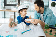 © Viacheslav Yakobchuk - Interesting discoveries. Cheerful little boy in a hard hat and his loving father sitting in the office and examining the models of constructions