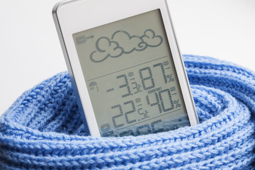 Wall Mural - Weather station device in the light blue knitted scarf on a light background. Closeup, selective focus