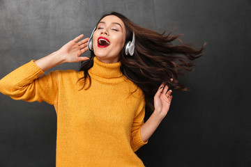 Poster - Playful brunette woman in sweater and headphone listening music