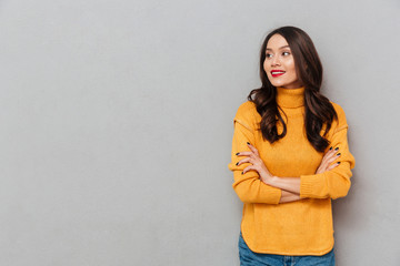 Poster - Smiling woman in sweater with crossed arms looking away