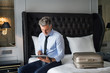 Mature businessman with tablet in a hotel room.