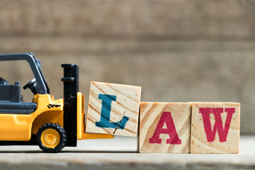 Poster - Toy yellow forklift hold letter block L to complete word law on wood background