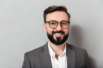 Sticker - Close up portrait of caucasian unshaved man in eyeglasses looking on camera with sincere smile, isolated over gray background