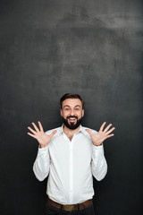 Wall Mural - Image of male office worker gesturing on camera with hands up, being cheerful over dark gray background