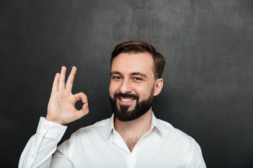 Canvas Print - Close up photo of bearded guy smiling and gesturing with OK sign expressing good choice, being isolated over graphite background