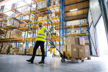 Male warehouse worker pulling a pallet truck.