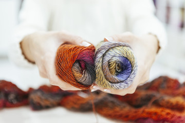 Wall Mural - woman holding a couple of earth tones wool of yarns isolated on white background