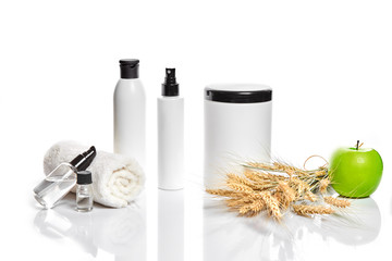 Spa cosmetics, jar of cream, oil with wheat, white cosmetic bottles with apple and wheat towel, candle, soap isolated on white. Without label.