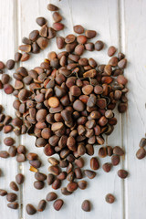 Poster - Heap of fresh and ripe pine nuts over white wooden table.