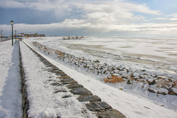 Wall Mural - Winter landscape with snow and frozen sea near harbor and beach Urk, Dutch fishing village at the IJsselmeer