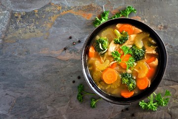 Wall Mural - Homemade chicken vegetable soup, overhead view on a dark slate background