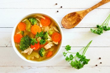 Wall Mural - Homemade chicken vegetable soup, above scene on a white wood background
