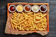 French fries on big wooden tray with sauces