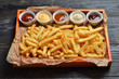 French fries on big wooden tray with sauces