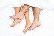Close up of the feet of a couple on the bed.