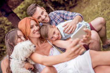 Wall Mural - Smiling young family taking selfie in the park.