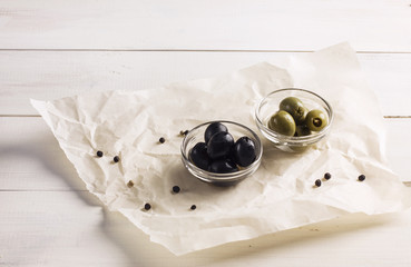 Green and black pickled olives on a white background