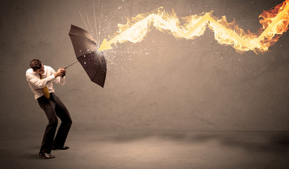 Wall Mural - Business man defending himself from a fire arrow with an umbrella