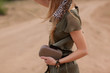 Girl in silk jumpsuit, details and lots of accessories, style of safari, side view
