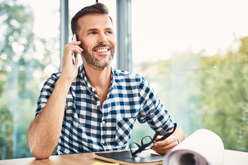 smiling designer talking on the phone sitting at desk in modern office