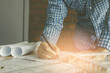 © PhotoJuthamat - Concept architects,engineer holding pen pointing equipment architects On the desk with a blueprint in the office, Vintage, Sunset ligth.Selective Focus
