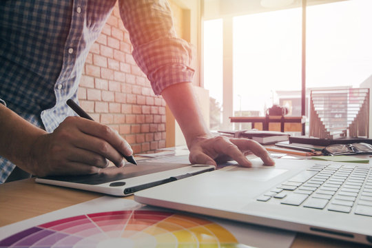 Designer graphic creative ,holding Mouse pen,working laptop in  office with sunset background,Selective focus.