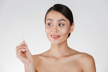 Canvas Print - Beauty portrait of attractive candid dark-haired woman looking at small tweezers holding in her hand, isolated over white background