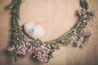 Easter Still life closeup with decorative eggs in pastel pink colours, rope, ribbon and button on flower wreath on the wooden background