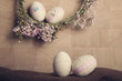 Easter background with Easter eggs and flower wreath, pastel colours decoration from rope, ribbon with wooden background