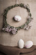 Easter Still life with decorative eggs in pastel colours, rope, ribbon and button with flower wreath on the wooden background