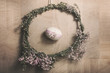Easter background with Easter egg inside the flower wreath, pastel colours decoration from rope, ribbon and button with wooden background