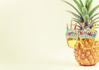 yellow fancy glasses on fresh pineapple, copy space on left, summer birthday concept, pastel color tone