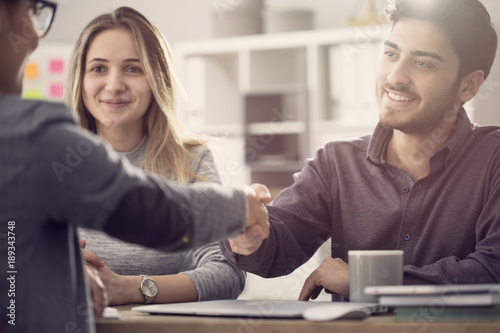 Fotografie, Obraz Young couple shaking hands with a female agent