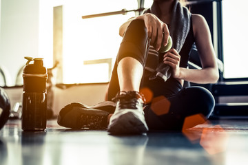 sport woman sitting and resting after workout or exercise in fitness gym with protein shake or drink