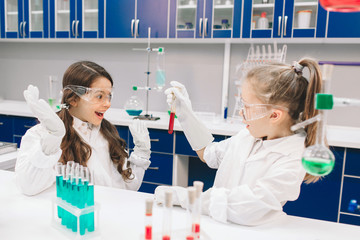 two little kids in lab coat learning chemistry in school laboratory. young scientists in protective 