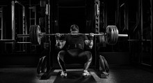 Professional Athlete Sits With A Barbell On His Shoulders And Prepares To Stand With Her.