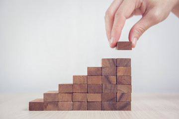 close up woman hand arranging wood block stacking as step stair. business concept growth success pro