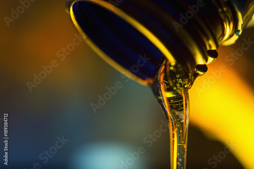 Fotografía Liquid stream of clean oil flows from the neck of the plastic bottle close-up