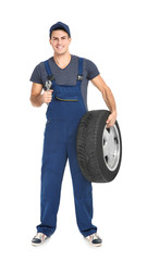 Wall Mural - Young mechanic in uniform with car tire on white background