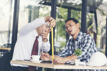 Businessman and building contractor are discussion Team Meeting using measure tape to evaluate. Industry Business Work Concept