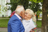 Fototapeta  - Black and white photo. Elderly man kisses an elderly lady. Concept: family, love, date. Fancy clothes, bright makeup.