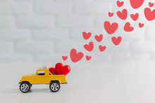 Valentines Day Theme,Red Hearts In Toy Yellow Truck Car Carrying To Lover.Love Delivery Concept.