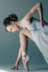 Wall Mural - young ballerina in white dress stretching in studio