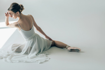 Wall Mural - back view of elegant ballerina sitting in white dress and ballet shoes