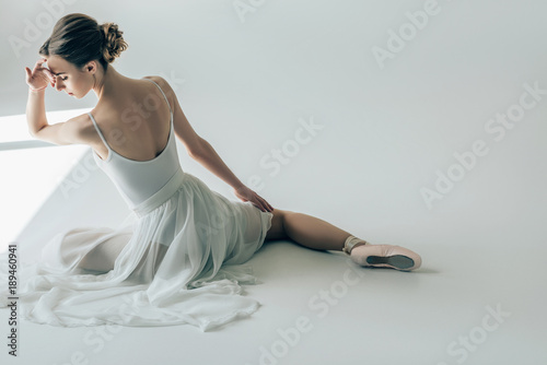 Fotomural back view of elegant ballerina sitting in white dress and ballet shoes