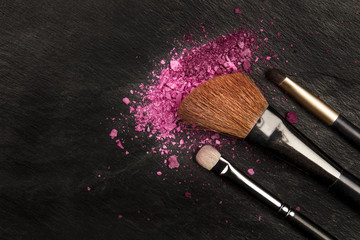 Wall Mural - Closeup of makeup brushes with eye shadow on black with copy space