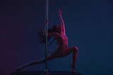 attractive sporty girl dancing with pole on blue