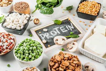Wall Mural - Healthy diet vegan food, veggie protein sources: Tofu, vegan milk, beans, lentils, nuts, soy milk, spinach and seeds. Top view on white table.